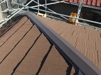 新しい棟板金とブラウン色のエコグラーニで葺き替え工事が完了